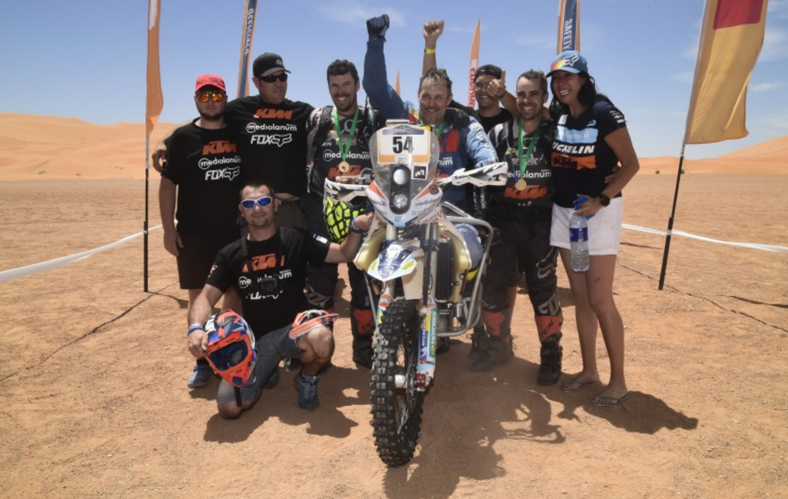Nicola Dutto and his team after a race, with him sitting on his motorcycle accommodated to allow him to race as a paraplegic. 