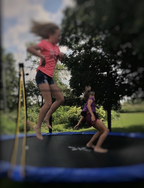 two teen girls jumping on a trampoline at the Sharritt's farm