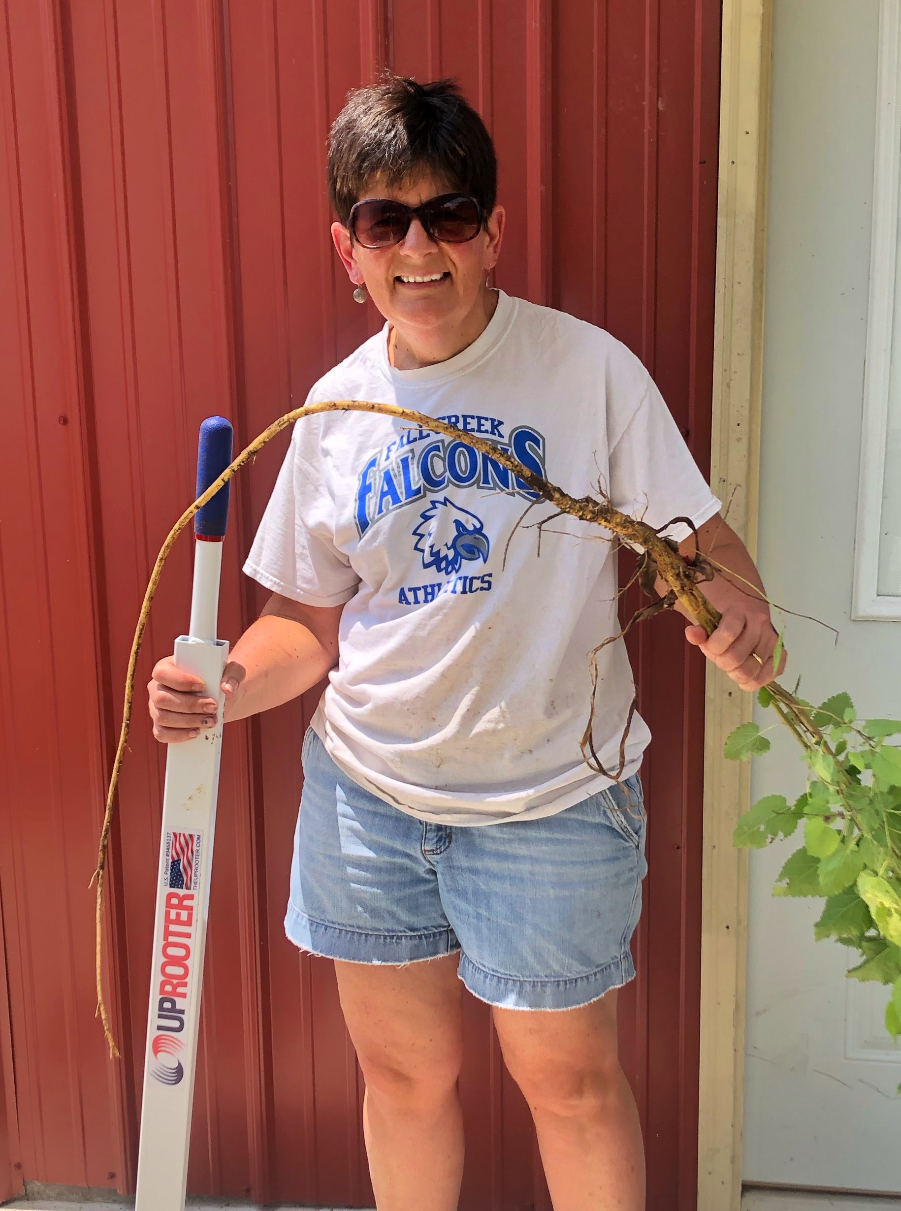 Bev holding the Uprooter and a tree removed with the tool