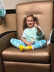 Kenzie setting in a chair giving a thumbs up.