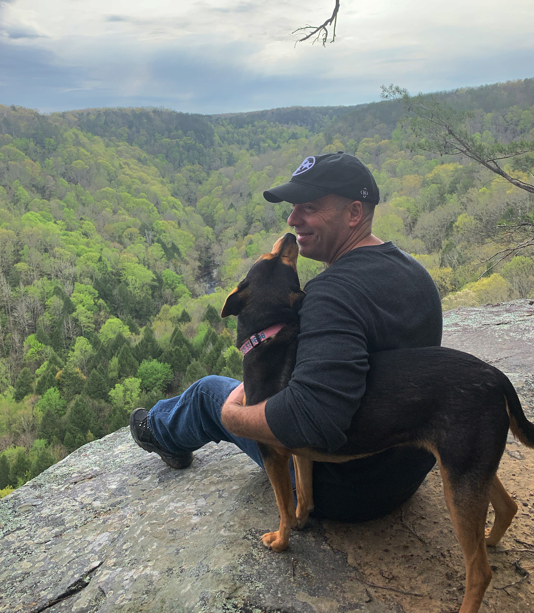 Mark Pruett sitting on rock with a dog