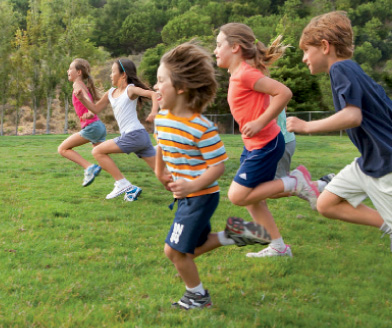 5 elementary aged students running through the grass