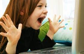 excited preschool girl with open hands raised near her face looking at device screen