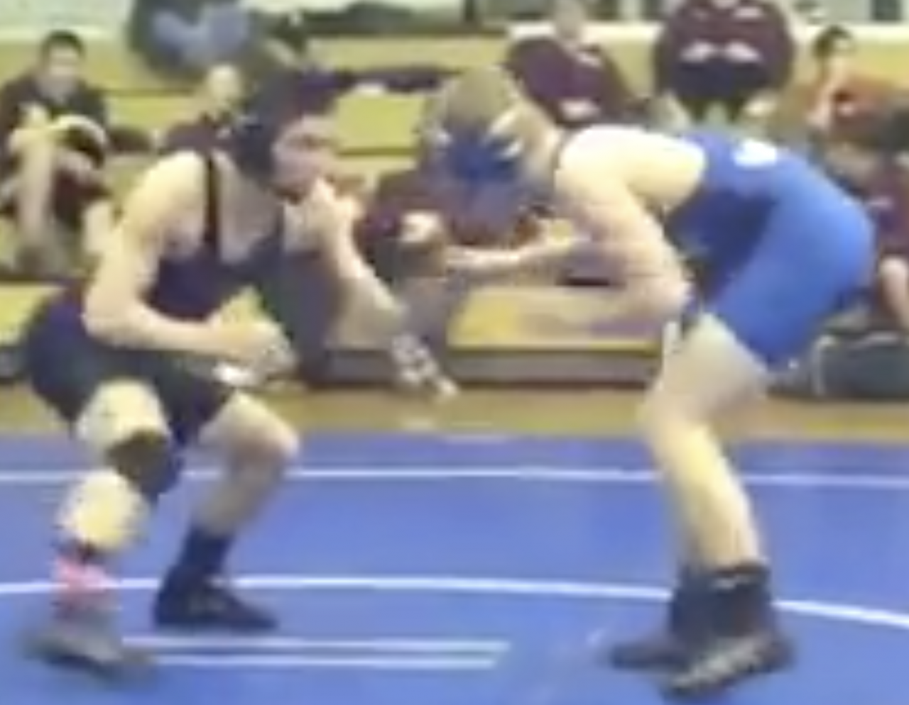 Derek standing in wrestling stance, facing an opponent in high school wrestling