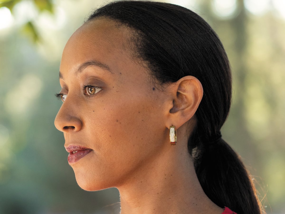 Haben Girma, a woman with light brown skin looks into the distance. Her dark hair is pulled back and she is wearing small gold earrings. 