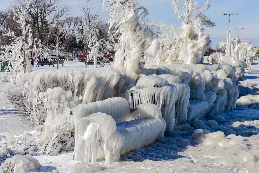 bench and bushes in a park near Lake Michigan covered in ice.
