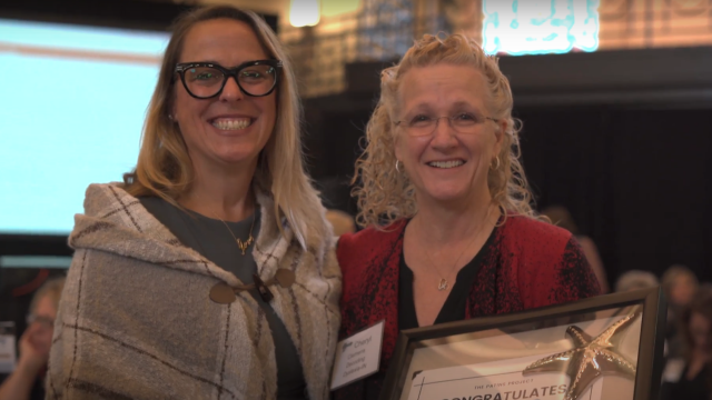 Dr. Kelly Grillo and Cheryl Clemens stand next to each other and smile. Cheryl holds the Starfish Award.