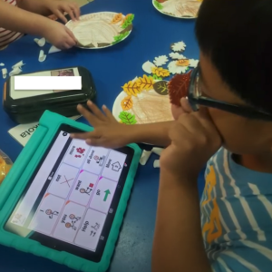 First grader using AAC app on device.